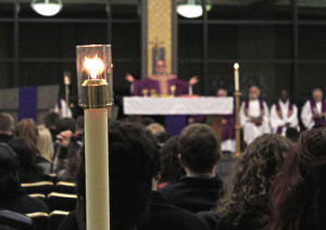 Photo by Taylor Miles | The Duquesne Duke. A candle shines over Duquesne students and friends and family of late football player Chris Johnson during a memorial Mass Sunday night in the Power Center Ballroom. Johnson, 22, died Feb. 27 from a self-inflicted gunshot wound. 